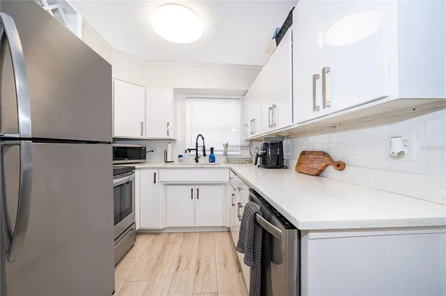 a kitchen with a sink a refrigerator and white cabinets