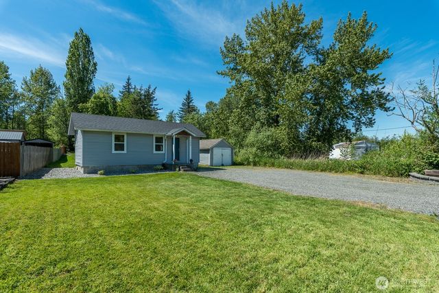 a backyard of a house with plants and large tree