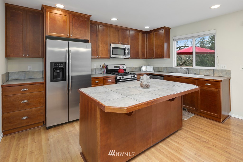 2425 194th Street Southeast, Unit 40 Bothell, WA 98012 - Photo 5 of 20 a kitchen with stainless steel appliances granite countertop a kitchen island a stove a refrigerator a sink and dishwasher wooden cabinets with wooden floor