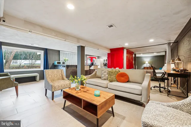 a living room with furniture a red rug and a lamp