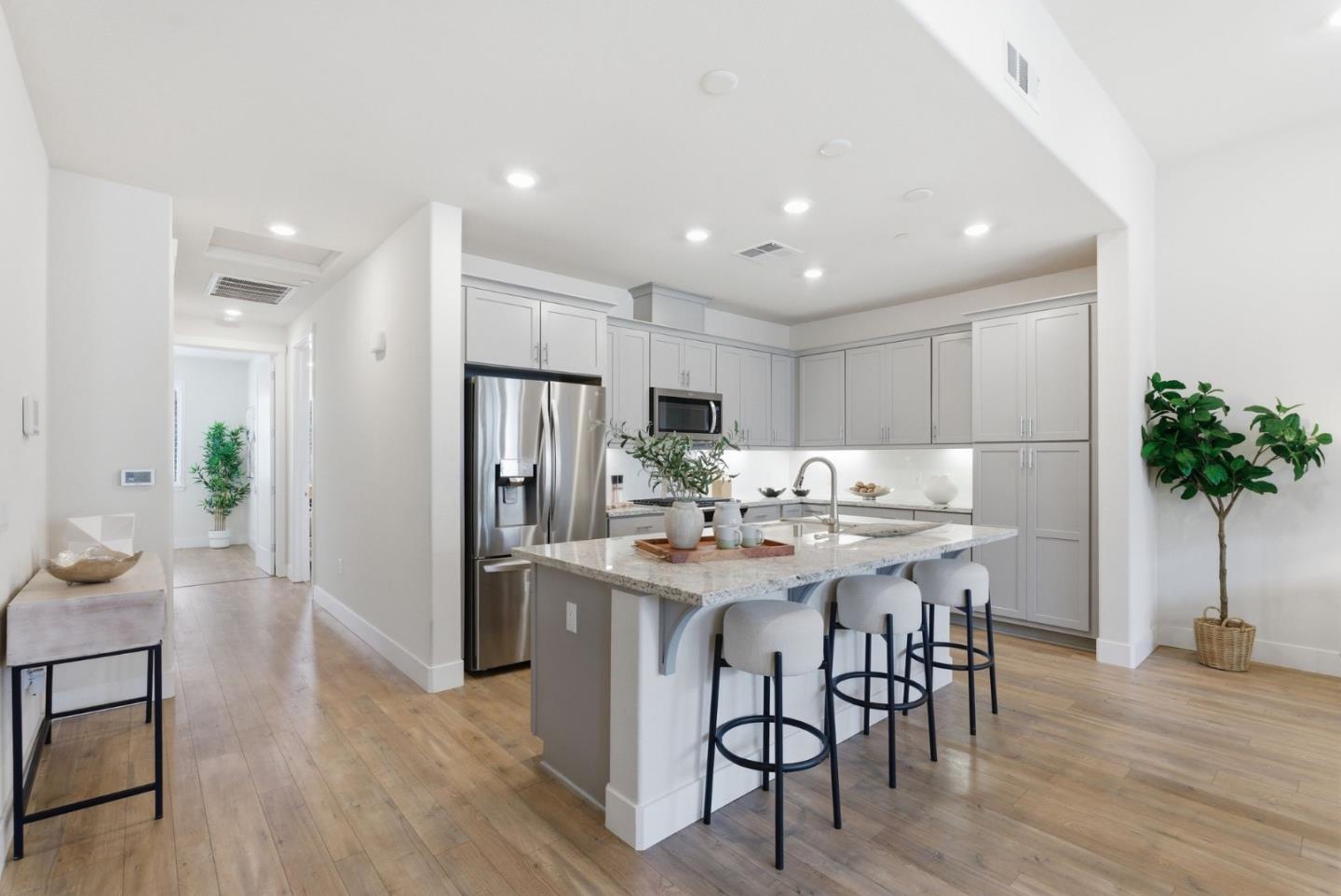 195 Carson Falls Common Fremont, CA 94539 - Photo 16 of 52 a kitchen with stainless steel appliances kitchen island granite countertop a table chairs refrigerator and sink