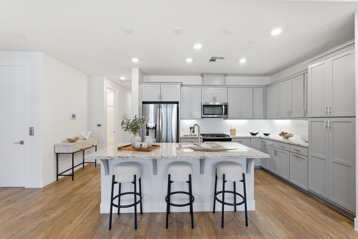 195 Carson Falls Common Fremont, CA 94539 - Photo 9 of 52 a kitchen with stainless steel appliances kitchen island granite countertop a dining table chairs stove refrigerator and cabinets