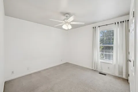 an empty room with a ceiling fan and a window