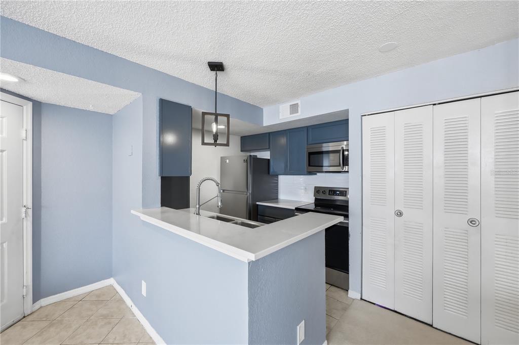 5108 Conroy Road, Unit 1724 Orlando, FL 32811 - Photo 12 of 40 a kitchen with stainless steel appliances a refrigerator sink and microwave