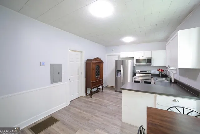 a kitchen with stainless steel appliances a refrigerator a stove a sink a dining table and chairs with wooden floor