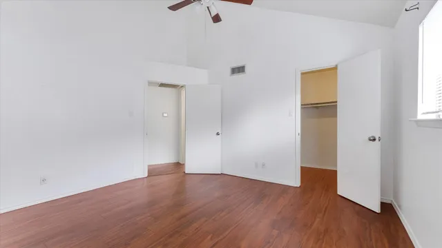 an empty room with wooden floor and windows