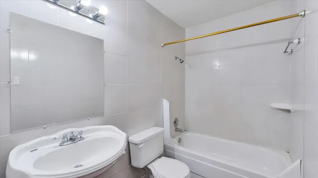 a bathroom with a bathtub shower sink and a toilet