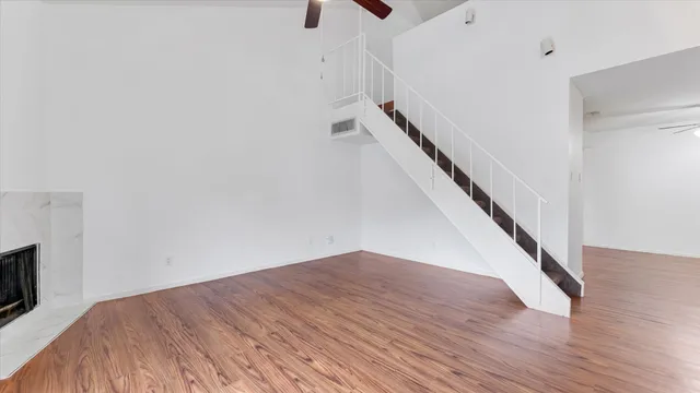 a view of an empty room with wooden floor and stairs