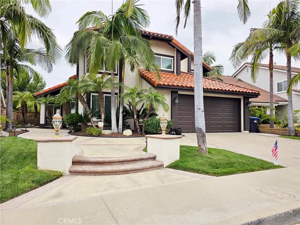 a view of a white house with a small yard plants and palm trees