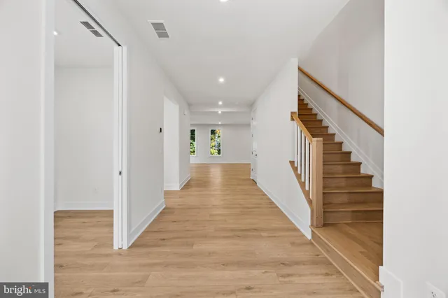 a view of a hallway with wooden floor and a room
