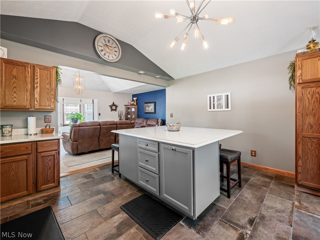 5245 Center Road Philo, OH 43771 - Photo 7 of 39 Kitchen with vaulted ceiling, a kitchen island, gray cabinetry, dark tile flooring, and a breakfast bar
