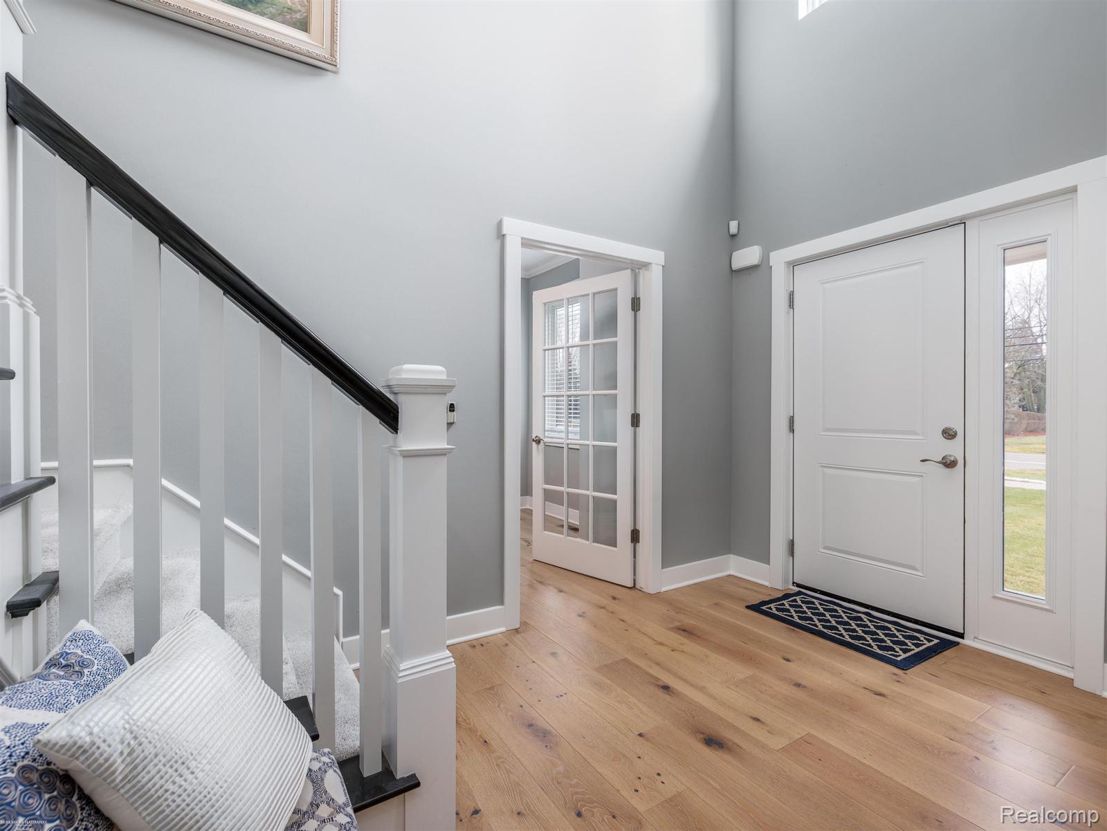 47705 Card Road Macomb, MI 48044 - Photo 5 of 53 Foyer featuring wood-finish flooring, a white paneled entry door with sidelight, and a staircase with white spindles and a black handrail
