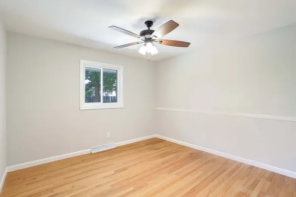 an empty room with wooden floor fan and windows