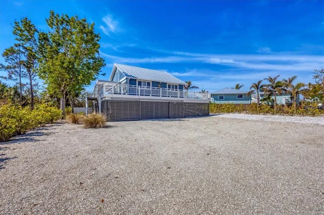 a front view of a house with a yard and a large tree