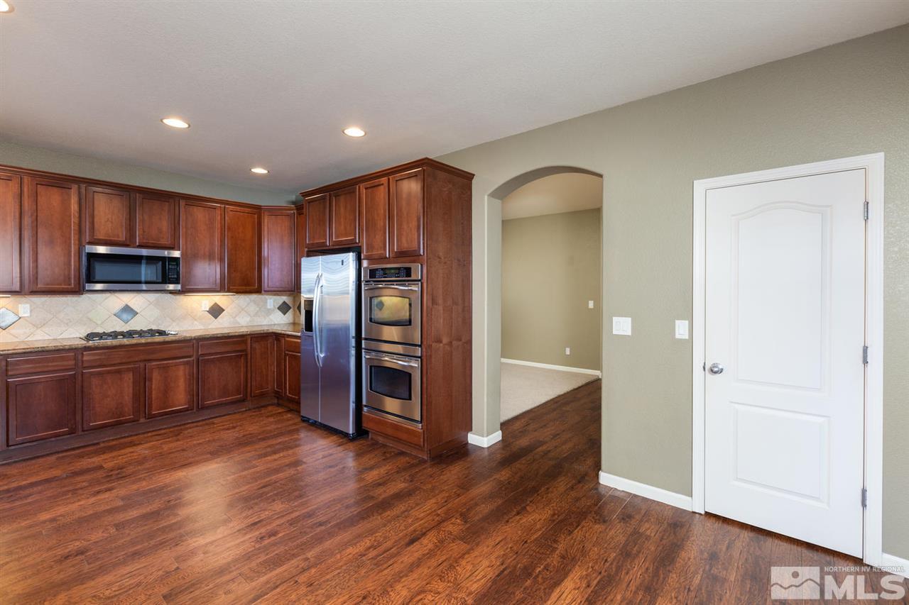 14005 Traveler Court Reno, NV 89521 - Photo 6 of 25 a kitchen with stainless steel appliances granite countertop a refrigerator a sink and wooden cabinets