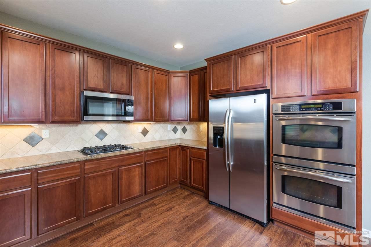 14005 Traveler Court Reno, NV 89521 - Photo 8 of 25 a kitchen with granite countertop wooden cabinets stainless steel appliances and a window