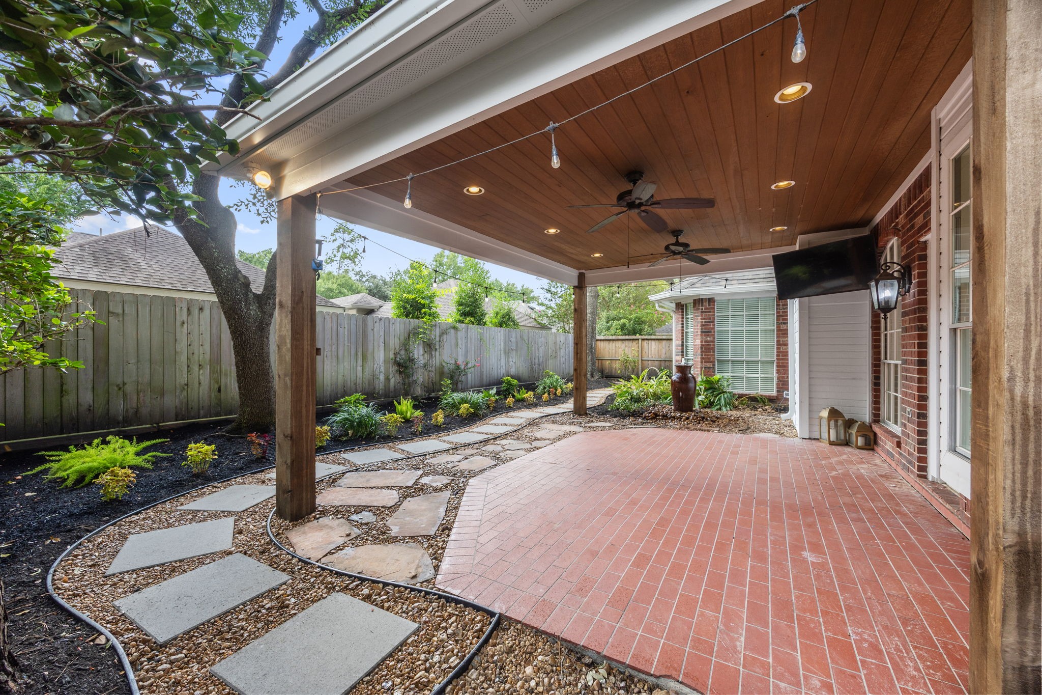9015 Rhapsody Lane Houston, TX 77040 - Photo 32 of 39 Winding stone pathways lead throughout the yard and connect to the expanded covered patio/deck, creating a charming outdoor space with plenty of character.