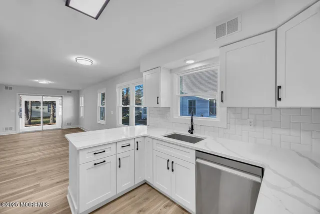 a kitchen with white cabinets and sink