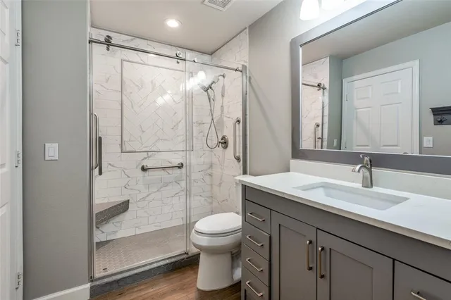 a bathroom with a granite countertop sink toilet a mirror and shower
