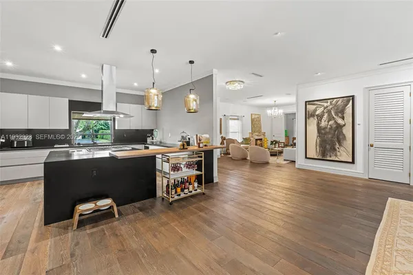 a kitchen with stainless steel appliances kitchen island granite countertop a refrigerator a stove a sink and a dining table with wooden floor