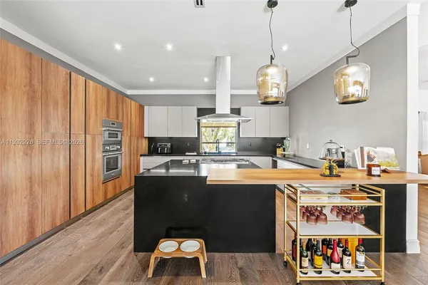 a kitchen with stainless steel appliances granite countertop a stove a sink dishwasher and a dining table with wooden floor