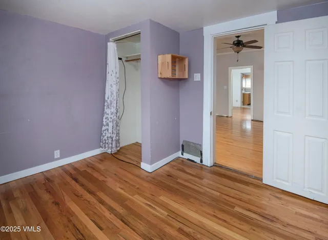 a view of a room with wooden floor a ceiling fan and a window