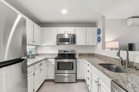 a kitchen with granite countertop white cabinets and white stainless steel appliances