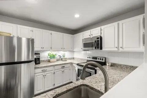 a kitchen with stainless steel appliances granite countertop a refrigerator sink stove microwave and cabinets