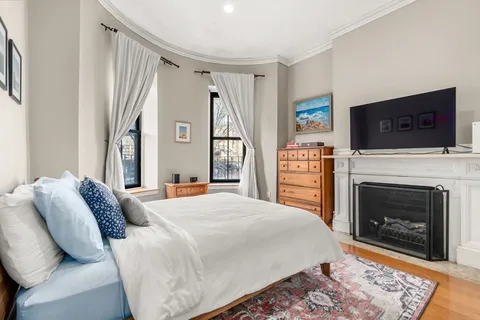 a bedroom with a bed a flat screen tv and a fireplace