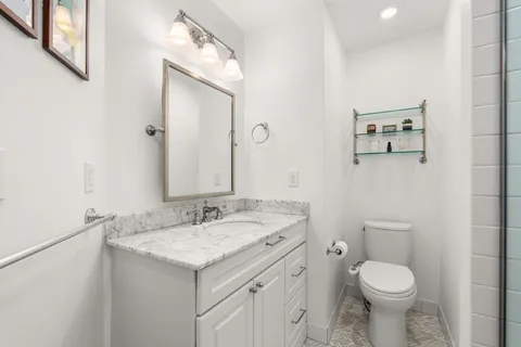 a bathroom with a granite countertop toilet sink and mirror