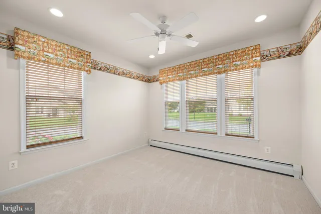 an empty room with a ceiling fan and windows