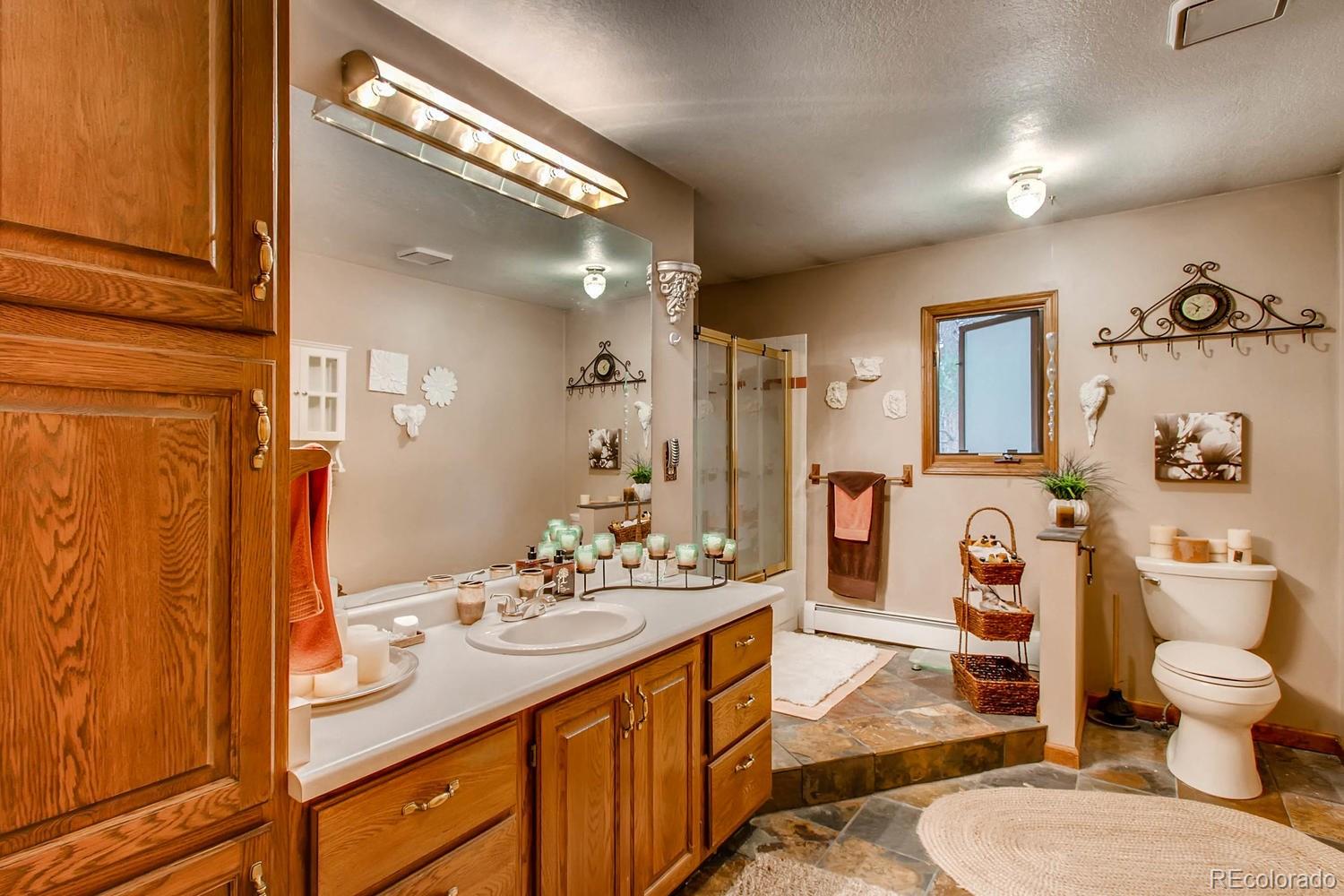 8060 Cyprus Road Colorado Springs, CO 80908 - Photo 18 of 28 a spacious bathroom with a sink a toilet a mirror and shower