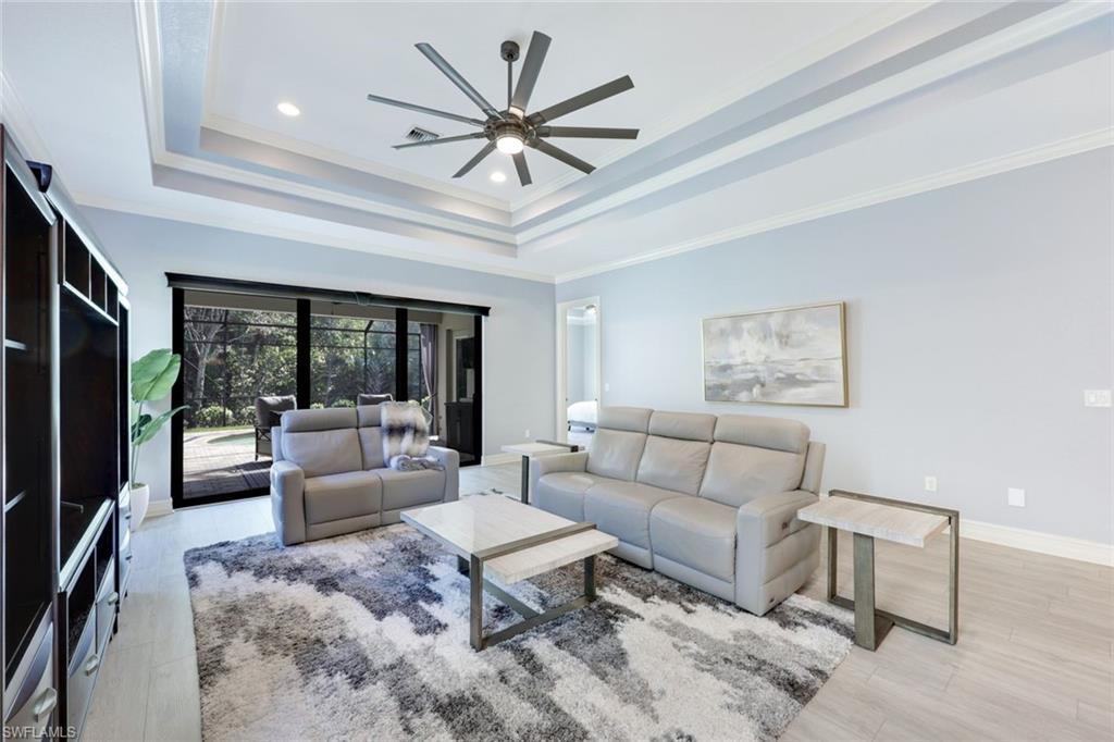 6592 Roma Way Naples, FL 34113 - Photo 11 of 41 Living room featuring a tray ceiling, crown molding, ceiling fan, and light wood-style floors