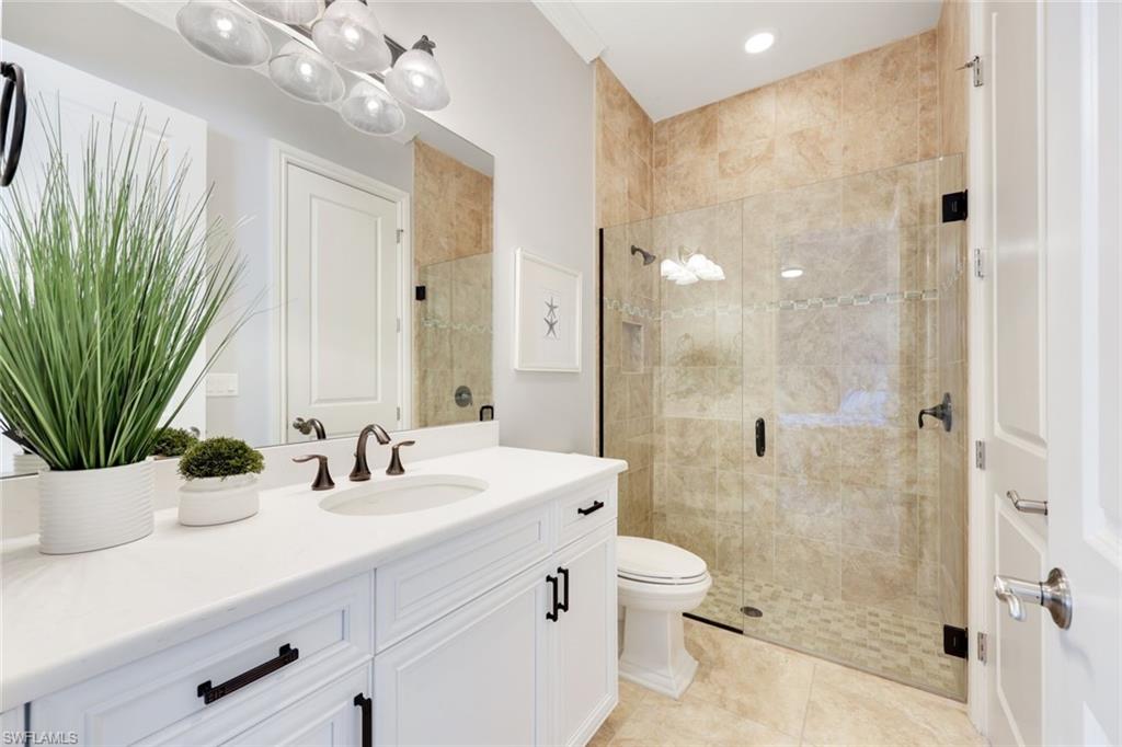 6592 Roma Way Naples, FL 34113 - Photo 16 of 41 Bathroom with tile patterned floors, white cabinetry, quartz counters and frameless shower door