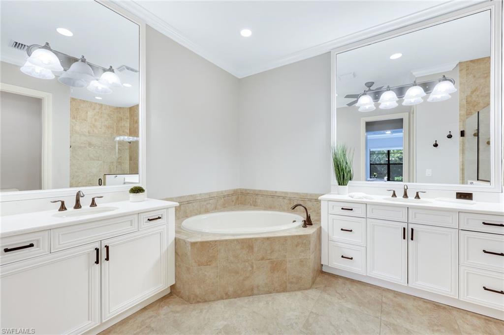 6592 Roma Way Naples, FL 34113 - Photo 17 of 41 Primary bathroom with tile patterned floors, white cabinetry, quartz counters, soaking tub and frameless shower door