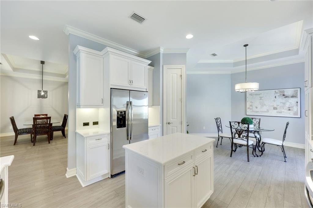 Kitchen with peninsula, white quartz counters, stainless appliances, light wood-type flooring, decorative light fixtures, and white cabinets