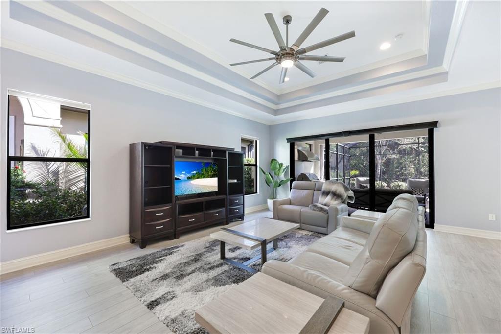6592 Roma Way Naples, FL 34113 - Photo 10 of 41 Living room featuring a tray ceiling, crown molding, ceiling fan, and light wood-style floors