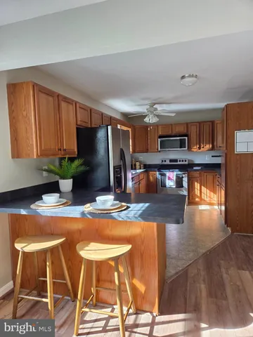 a kitchen with stainless steel appliances granite countertop a refrigerator a stove a sink dishwasher and cabinets with wooden floor