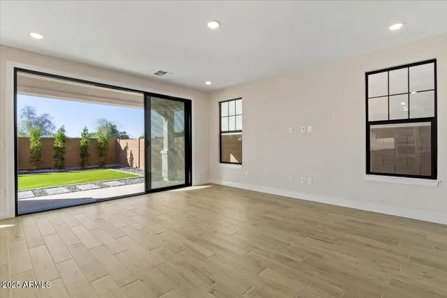 a view of an empty room with wooden floor and windows