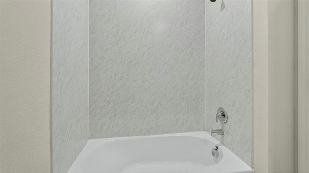 4008 Ripplewood Drive Lindale, TX 75771 - Photo 4 of 37 White bathtub with chrome fixtures and light-toned, textured wall surround