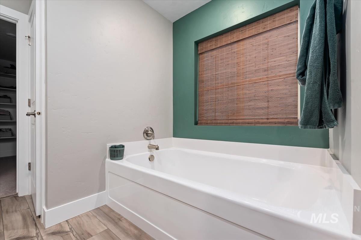 815 Knowledge Street Middleton, ID 83644 - Photo 31 of 49 Soaking tub with brushed nickel fixtures, wood-finish flooring, and a recessed window featuring a woven wood shade