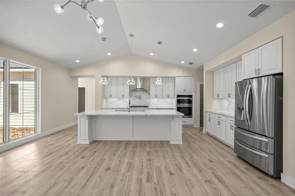 a large kitchen with stainless steel appliances a large counter top and wooden floors