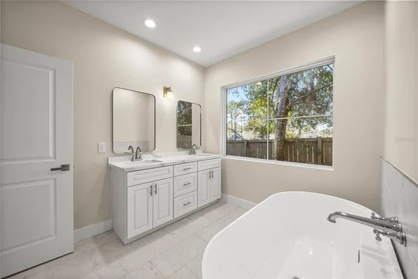 a bathroom with a double vanity sink and mirror with bathtub
