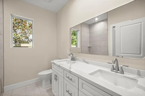 a bathroom with a granite countertop sink a toilet and a mirror