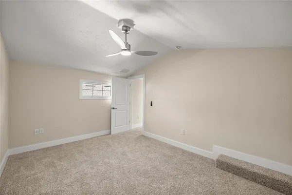 an empty room with a chandelier fan and windows