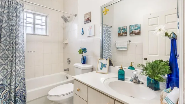 a bathroom with a granite countertop bathtub sink vanity mirror and toilet