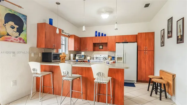 a kitchen with stainless steel appliances kitchen island granite countertop a refrigerator and a dining table