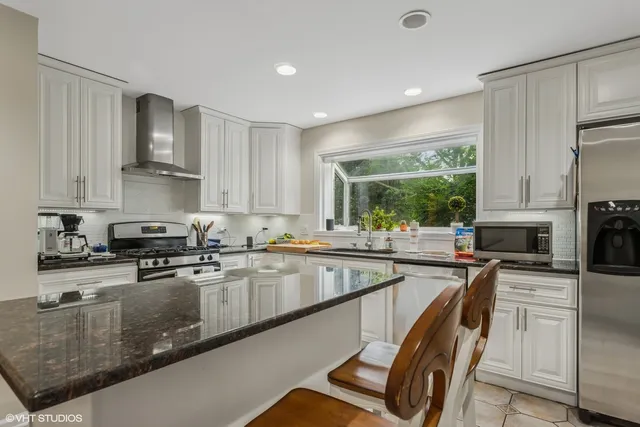 a kitchen with kitchen island granite countertop a stove sink and cabinets