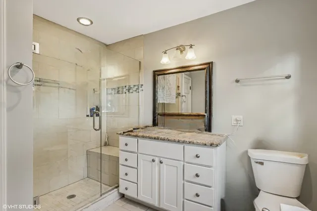 a bathroom with a granite countertop sink a mirror and a toilet