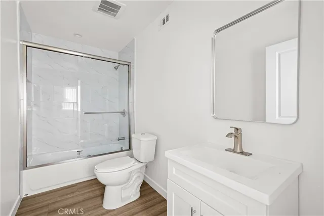 a view of empty room with wooden floor and kitchen